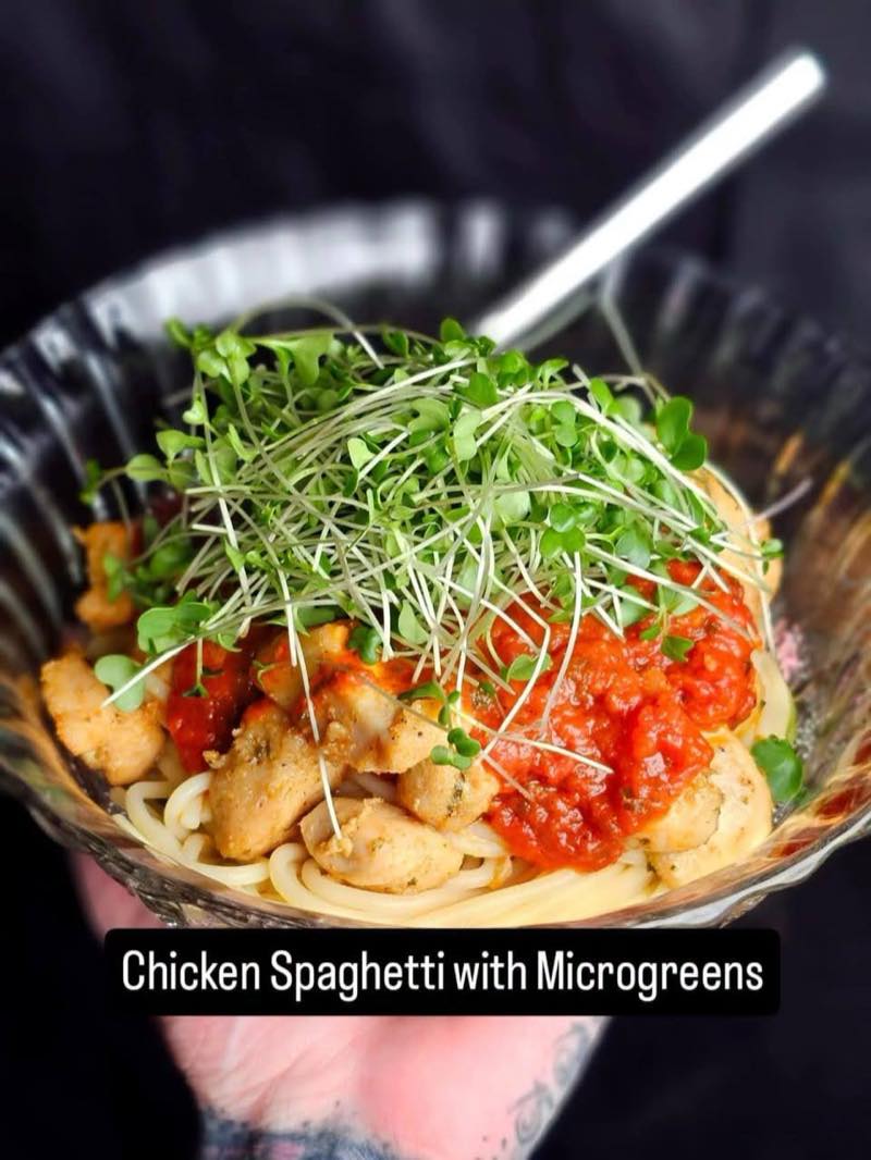 Chicken spaghetti in tomato sauce topped with microgreens